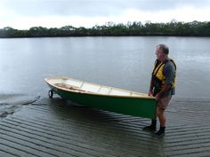 a man standing next to a green boat on top of a lake