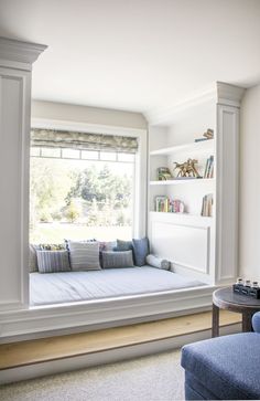 a window seat in the corner of a living room with bookshelves on either side