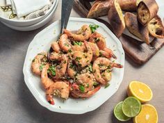 a white plate topped with shrimp next to sliced lemons