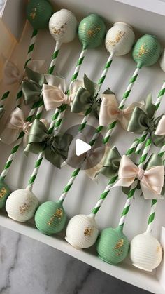 there are many green and white lollipops in the box with bows on them