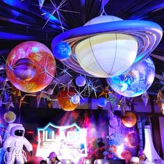 a room filled with lots of colorful lights and balloons hanging from the ceiling next to an astronaut figure