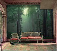 an empty room with two couches in front of a wall mural that has a forest scene on it