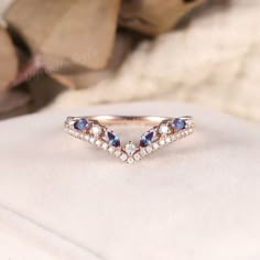 a diamond and blue sapphire ring on top of a white cloth with leaves in the background