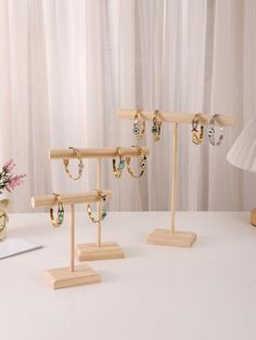 three pairs of earrings are on display in front of a lamp and vase with flowers