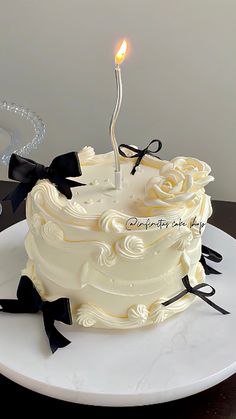 a white cake sitting on top of a plate with a lit candle in the middle