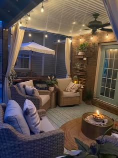 an outdoor living area with wicker furniture and string lights