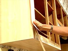 a person is holding something in their hand near the kitchen cabinet door and drawer drawers