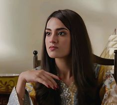 a woman with long dark hair sitting in a chair