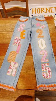 senior jeans Senior Overalls Front And Back, Senior Jeans Patchwork, Senior Jean Ideas High Schools, Painted Jeans For Hoco, Senior Sunset Outfits, Spirit Week Pants Ideas, Senior Jeans Patches, Senior Year Cheer Ideas