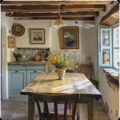 a table with flowers in a vase on top of it next to a kitchen counter