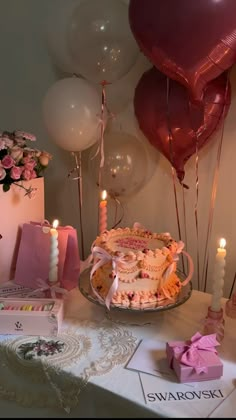 a table topped with a cake and balloons