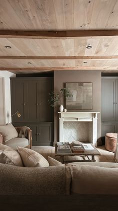 a living room filled with furniture and a fire place under a wooden ceiling above a fireplace