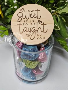 a jar filled with assorted candies and a wooden sign that says, how sweet it is to be taught