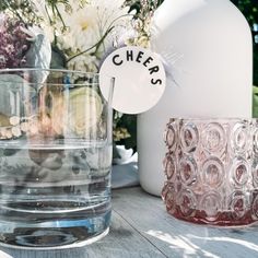 there are vases with flowers in them on the table next to water and other items