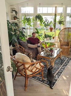 a man sitting in a living room next to a cat