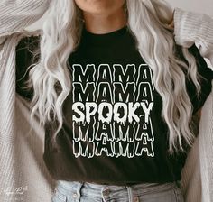 a woman with white hair wearing a black shirt that says mama spooky and has the words mama on it