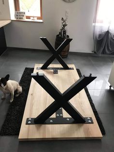 a dog is sitting on the floor in front of a table with an x design