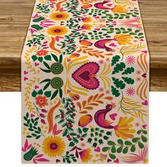 an image of a table runner with flowers and leaves on the top, in bright colors