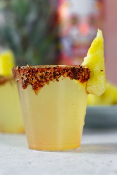 a pineapple tamarind vodka shot is garnished with a slice of lemon