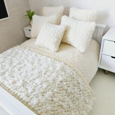 a white bed topped with lots of pillows next to a night stand and nightstands