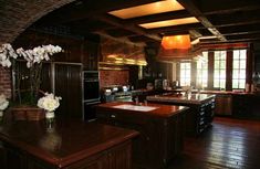 a large kitchen with wooden floors and brick walls, along with an island in the center