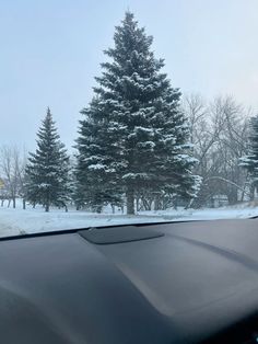 the windshield of a car on a snowy road with trees in the backgroud