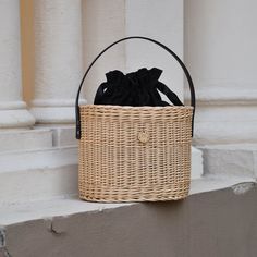 a wicker basket hanging on the side of a building with a black bag in it