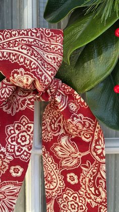 a close up of a red and white tie on a window sill with green leaves