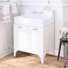 a white sink sitting next to a window in a bathroom on top of a hard wood floor