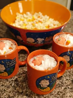 three orange mugs with marshmallows in them on a granite counter top