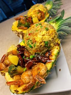 two pineapples with shrimp, broccoli and rice in them on a white plate