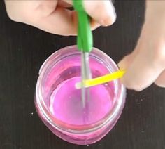 a person holding a toothbrush in a cup with pink liquid and yellow straws