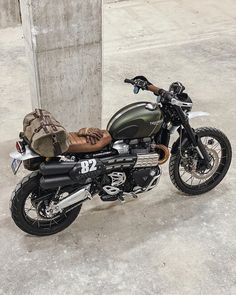 a motorcycle parked next to a cement wall with luggage on it's back end