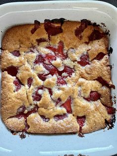 a square cake with strawberries in it on a white platter, ready to be eaten