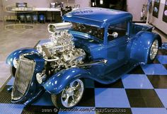 an antique blue car on display in a showroom with black and white checkered flooring