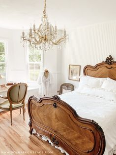 a bedroom with a bed, chair and chandelier in it's center