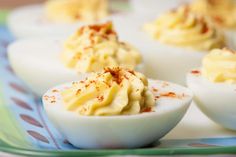 deviled eggs with mustard sprinkled on them sitting on a blue and green plate