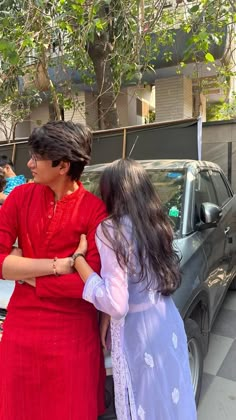 two women standing next to each other in front of a car