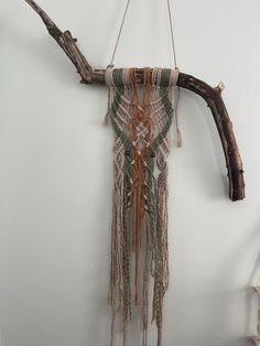 a piece of driftwood hanging on a wall next to a branch with beads and chains