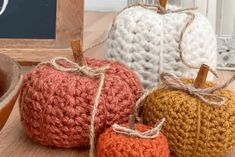 three crocheted pumpkins sitting on top of a wooden table