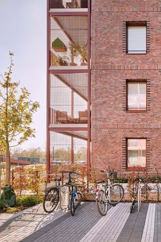 two bikes are parked in front of a brick building with multiple balconies on the side