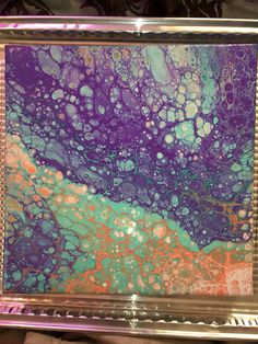 an abstract painting in purple, green and orange on a clear glass frame with beaded edges