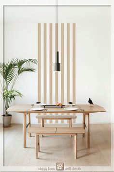 a dining table with two benches and a potted plant in front of the wall