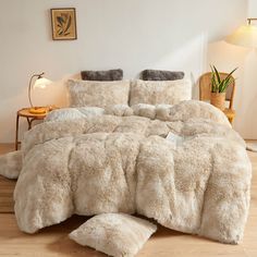 the comforter is made up with fluffy white furs and pillows on top of it