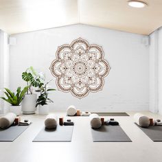 a room with yoga mats and plants on the floor in front of a white wall