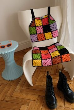 a crocheted chair sits next to a table with a pair of black boots