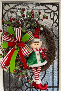 a christmas wreath with an elf doll hanging on it