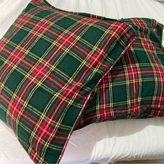 a green and red plaid pillow sitting on top of a bed