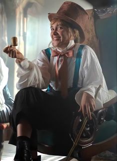 a man in a top hat and bow tie sitting on a chair holding a pipe