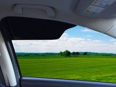 the view from inside a car looking at a green field